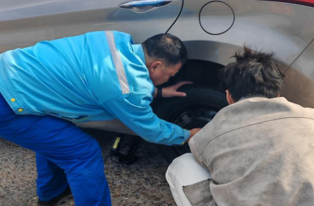 加油站員工幫助顧客更換故障輪胎 加油站員工幫助顧客更換故障輪胎